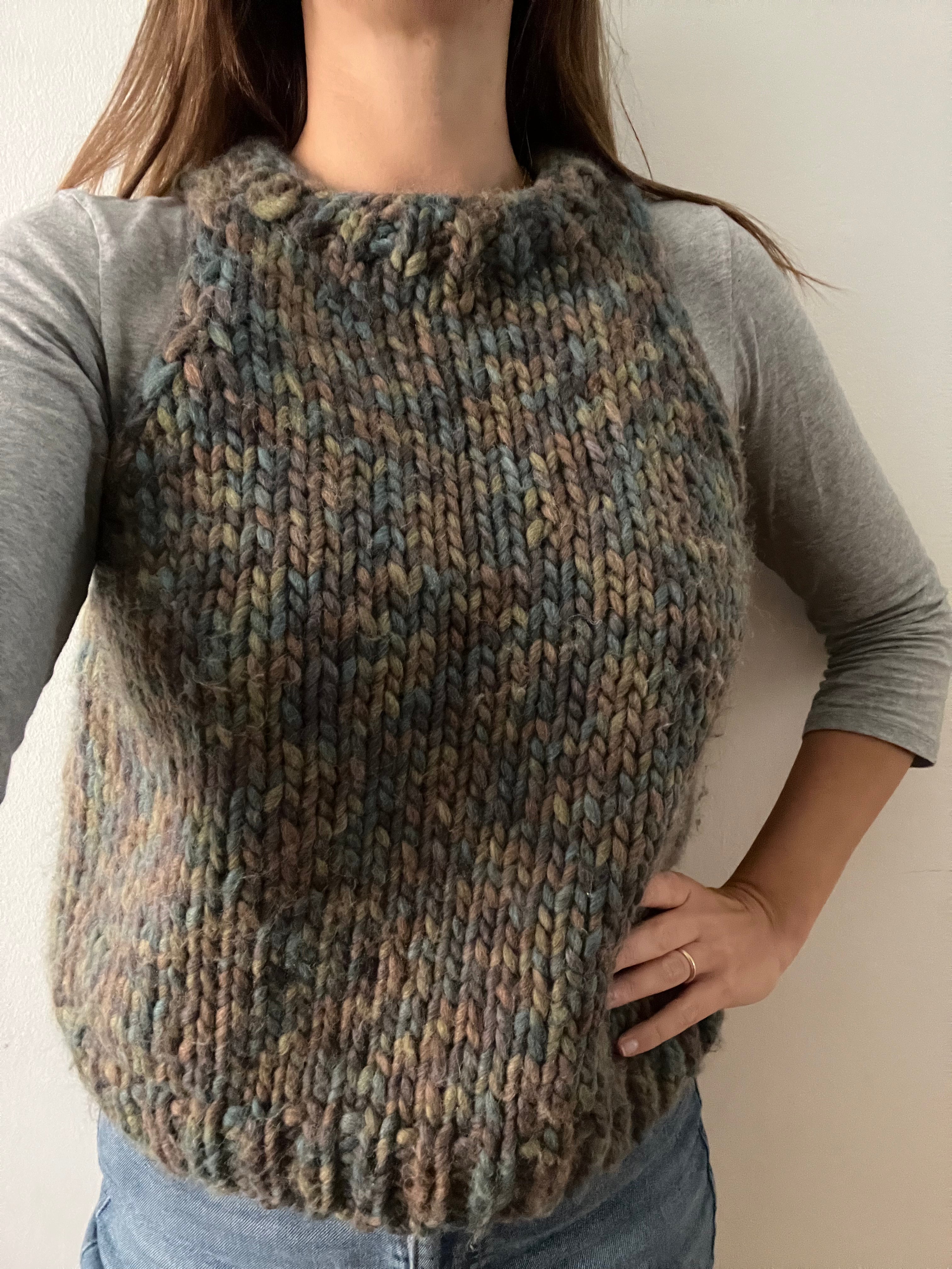 Gilet in lana fatto a mano, lavorato a maglia artigianale con filato multicolore, indossato sopra una maglia a maniche lunghe